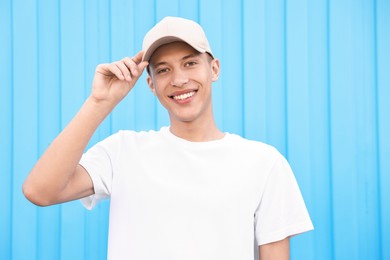 Portrait of smiling man in baseball cap near light blue wall