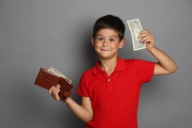 Cute boy with wallet and pocket money on grey background