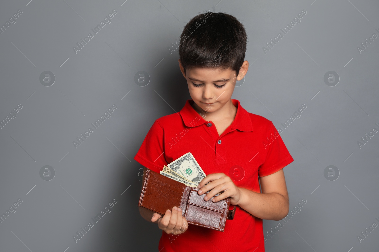 Photo of Cute boy with wallet and pocket money on grey background