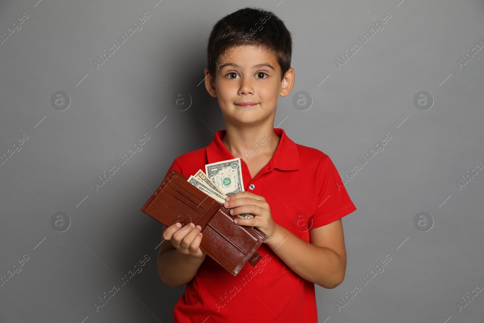 Photo of Cute boy with wallet and pocket money on grey background