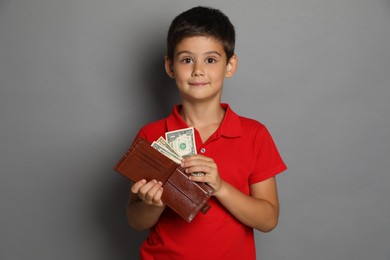 Photo of Cute boy with wallet and pocket money on grey background