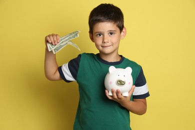 Cute boy with piggy bank and pocket money on yellow background