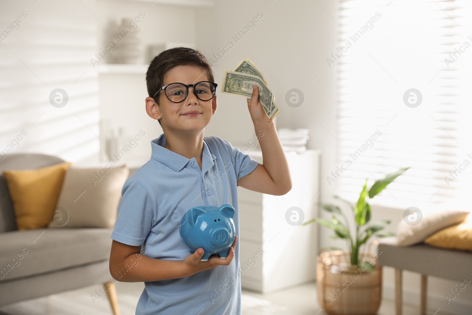 Photo of Cute boy with piggy bank and pocket money at home, space for text