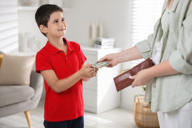 Photo of Mother giving pocket money to her son at home