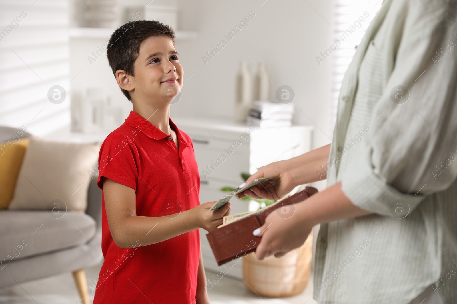 Photo of Mother giving pocket money to her son at home