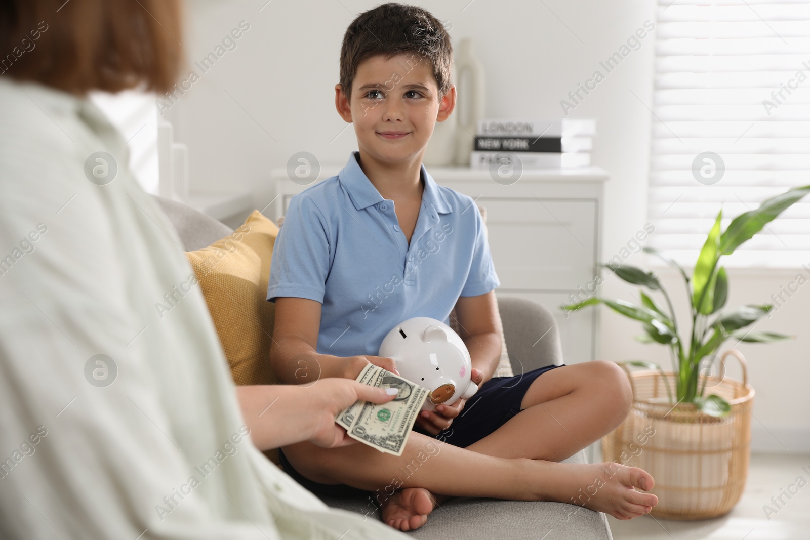 Photo of Mother giving pocket money to her son at home