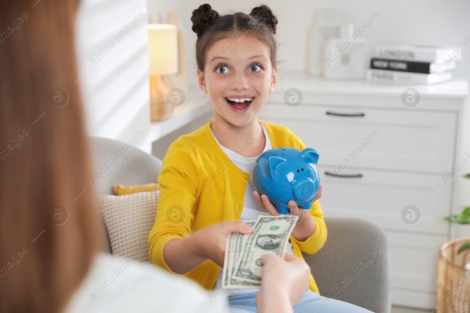 Photo of Mother giving pocket money to her daughter at home