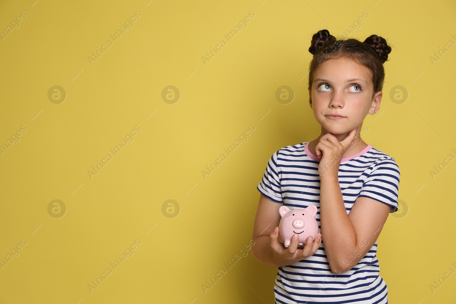 Photo of Pocket money. Cute girl with piggy bank on yellow background, space for text