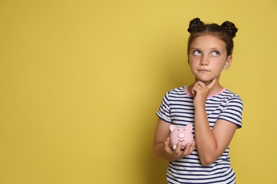 Pocket money. Cute girl with piggy bank on yellow background, space for text