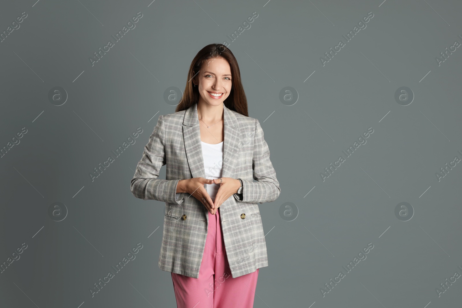 Photo of Beautiful woman in stylish jacket and pink pants on grey background