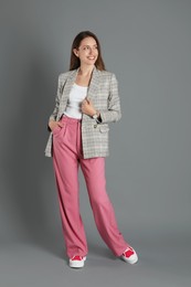 Photo of Beautiful woman in stylish jacket and pink pants on grey background