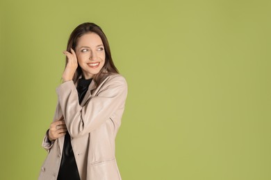 Photo of Beautiful woman in stylish beige jacket on olive background, space for text