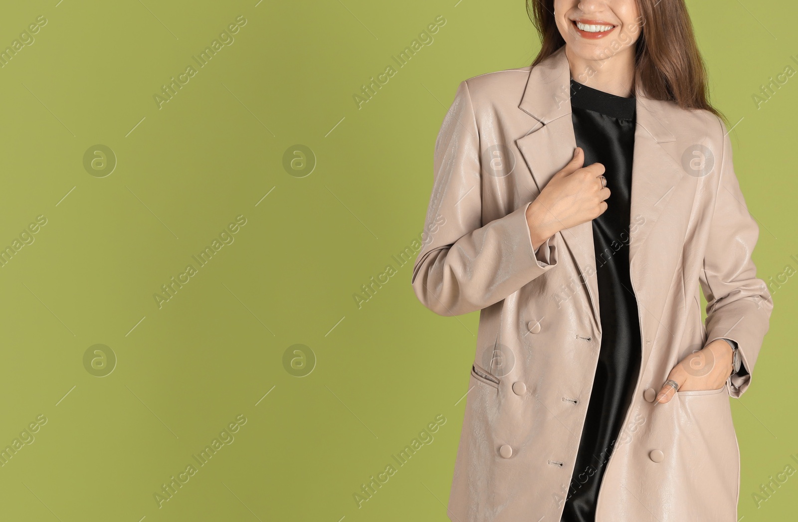 Photo of Beautiful woman in stylish beige jacket on olive background, closeup. Space for text