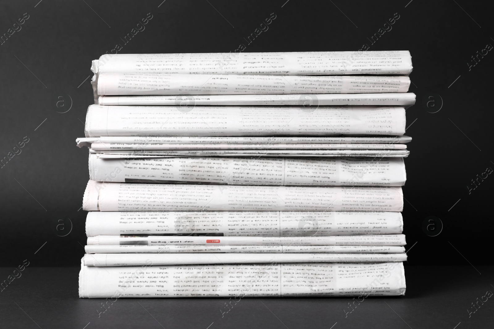 Photo of Stack of newspapers in different languages on black background