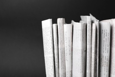 Many newspapers in different languages on black background, closeup. Space for text