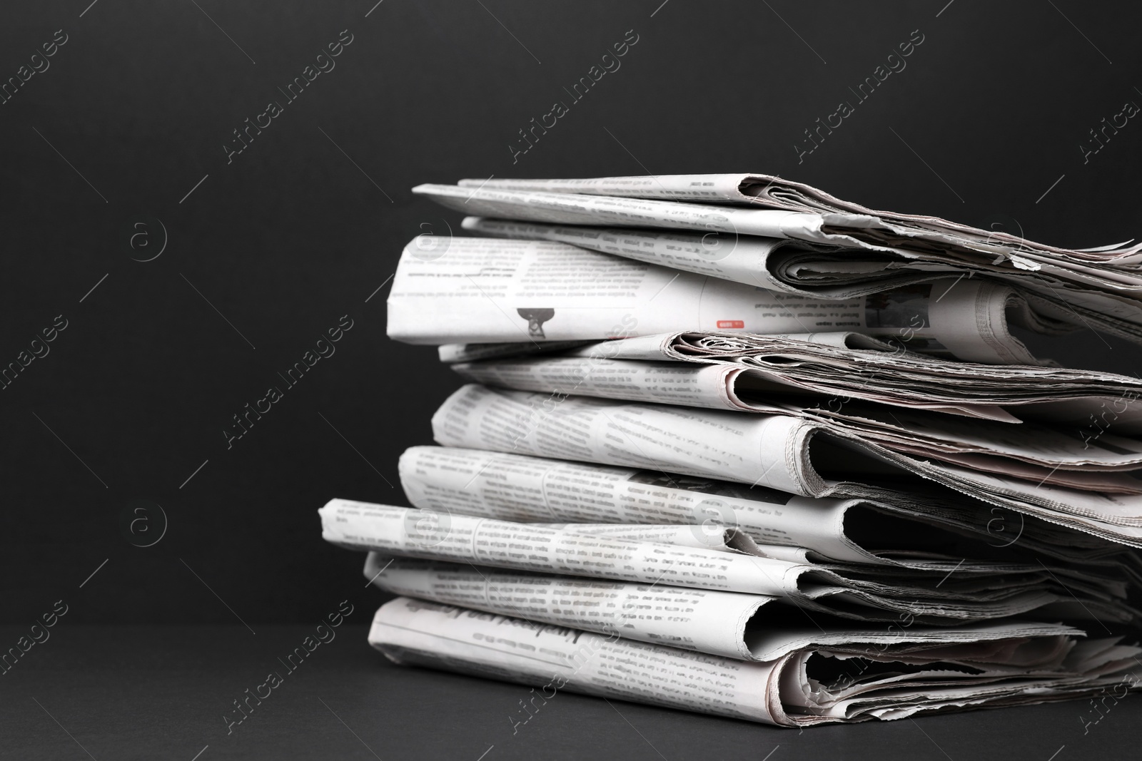 Photo of Stack of newspapers in different languages on black background