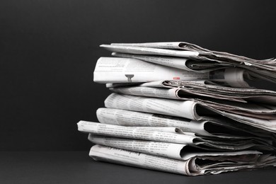 Stack of newspapers in different languages on black background