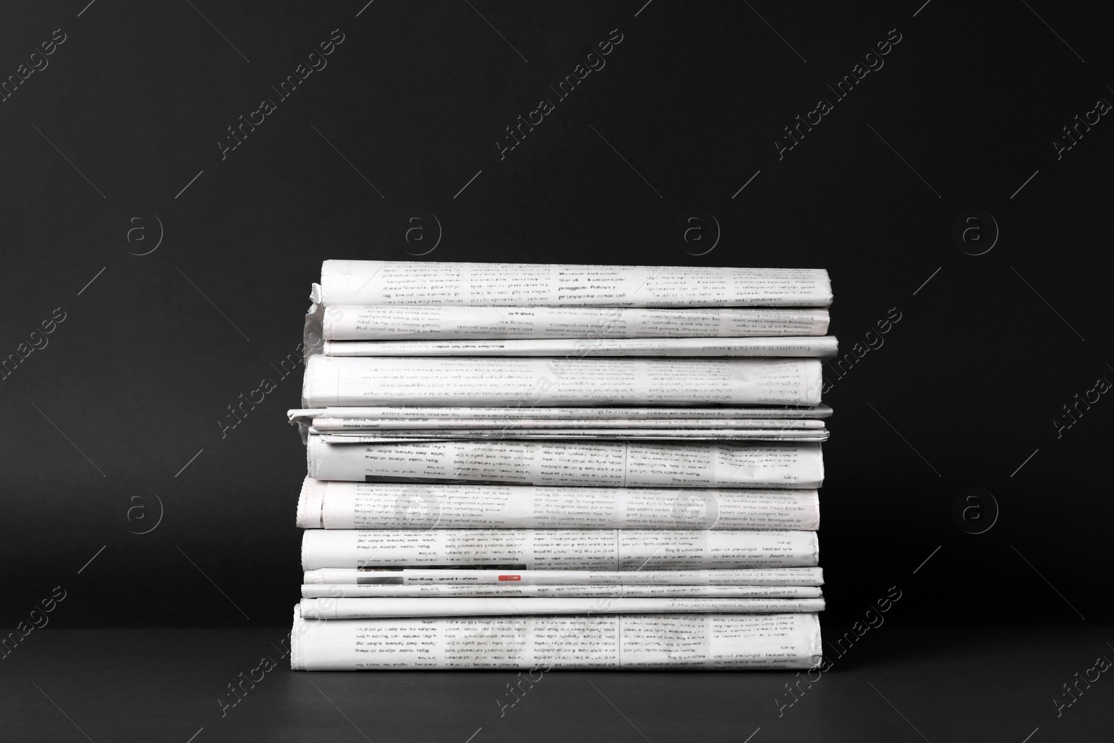 Photo of Stack of newspapers in different languages on black background