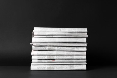 Stack of newspapers in different languages on black background