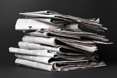 Photo of Stack of newspapers in different languages on black background, closeup