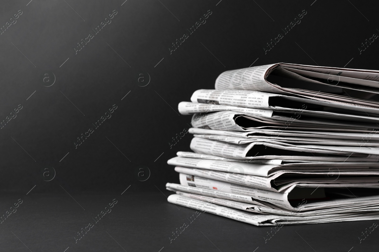 Photo of Stack of newspapers in different languages on black background. Space for text