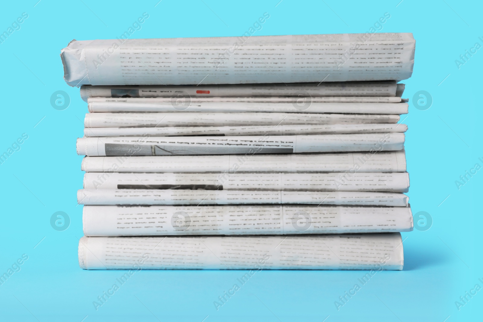 Photo of Stack of newspapers in different languages on light blue background