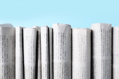 Photo of Many newspapers in different languages on light blue background, closeup