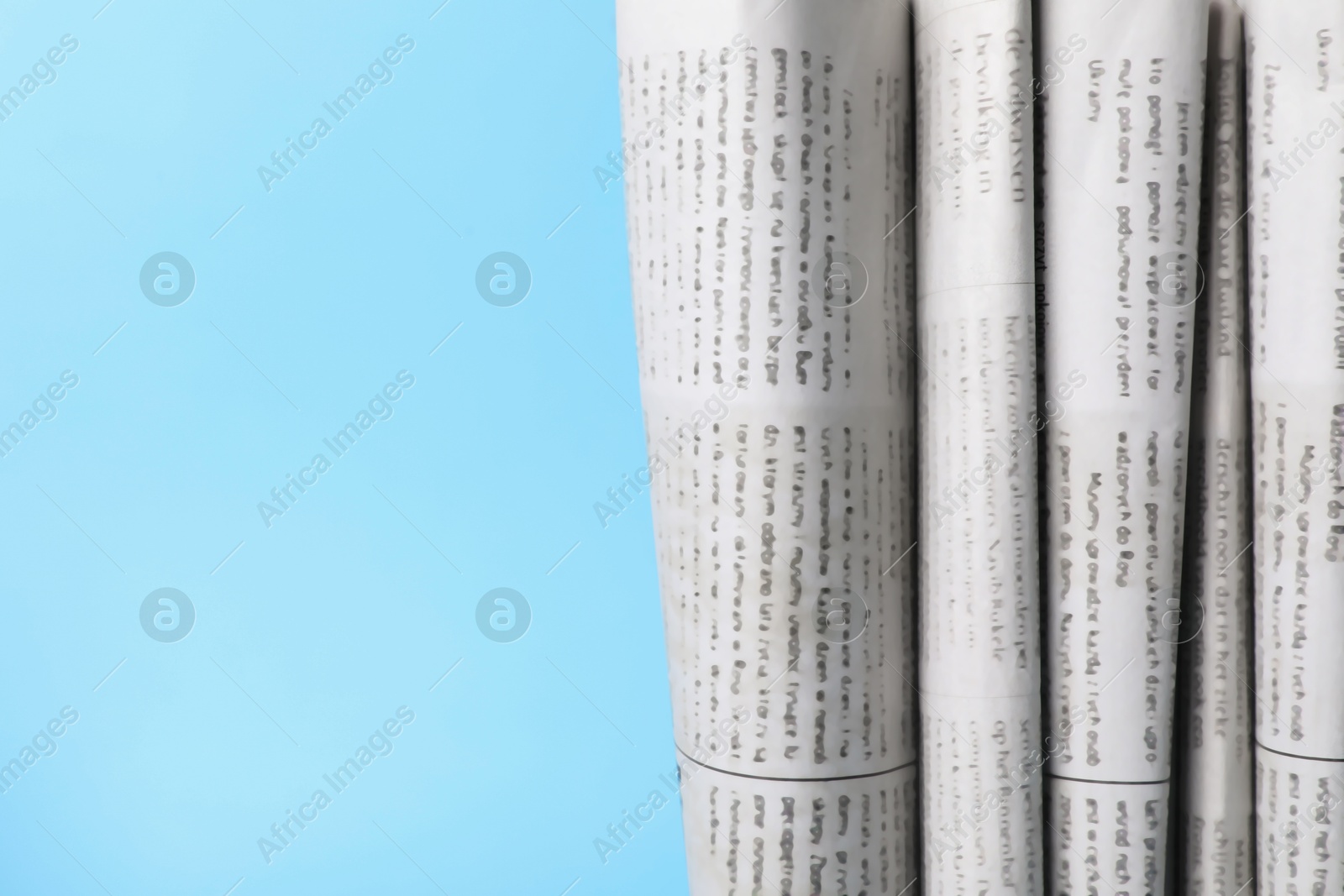 Photo of Many newspapers in different languages on light blue background, closeup. Space for text