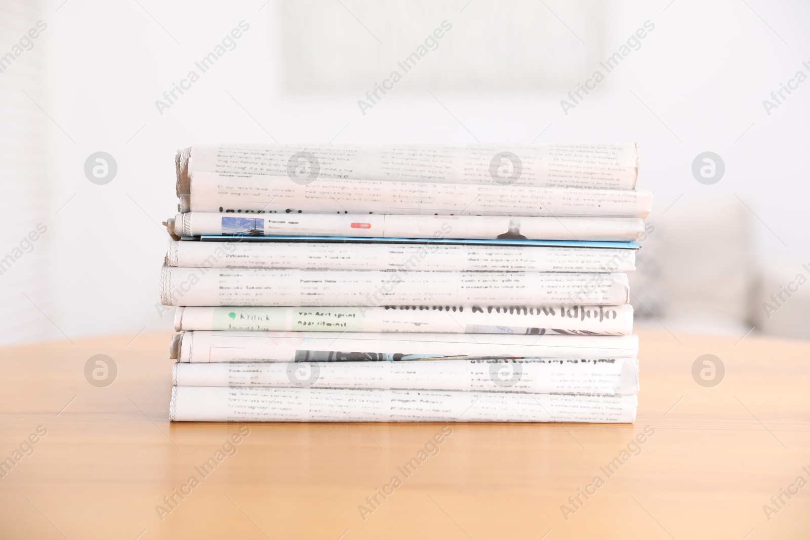 Photo of Stack of many newspapers in different languages on wooden table