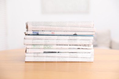 Photo of Stack of many newspapers in different languages on wooden table