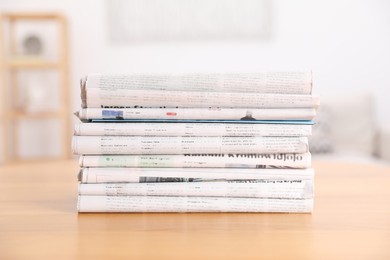 Stack of many newspapers in different languages on wooden table