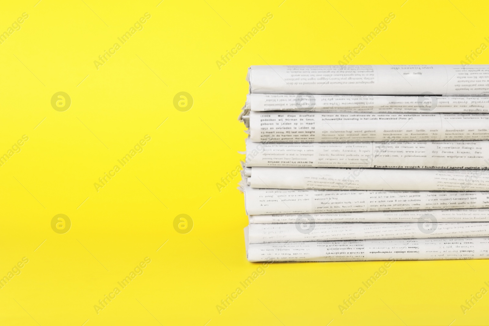 Photo of Stack of newspapers in different languages on yellow background, space for text