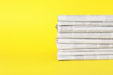 Stack of newspapers in different languages on yellow background, space for text