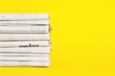 Photo of Stack of newspapers in different languages on yellow background, space for text