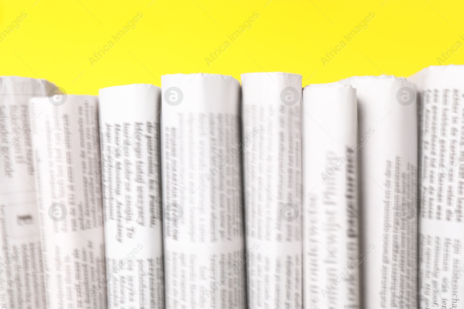 Photo of Many newspapers in different languages on yellow background, closeup