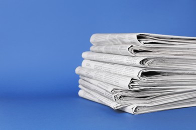 Stack of newspapers on blue background, space for text