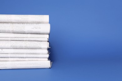 Stack of newspapers in different languages on blue background, space for text