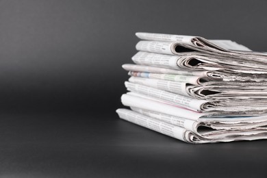 Stack of many newspapers on grey background, space for text