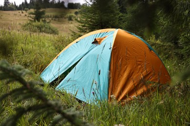 Photo of Tent on green grass in mountains. Camping equipment