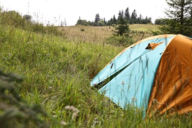 Photo of Tent on green grass in mountains, space for text