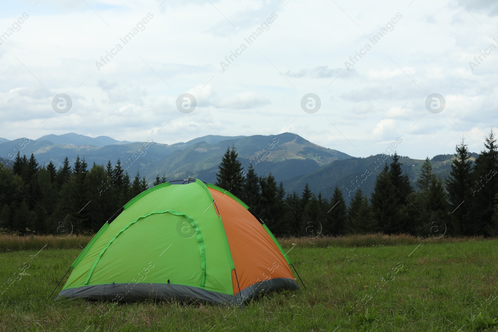 Photo of Tent on green grass in mountains, space for text