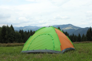 Photo of Tent on green grass in mountains. Camping equipment