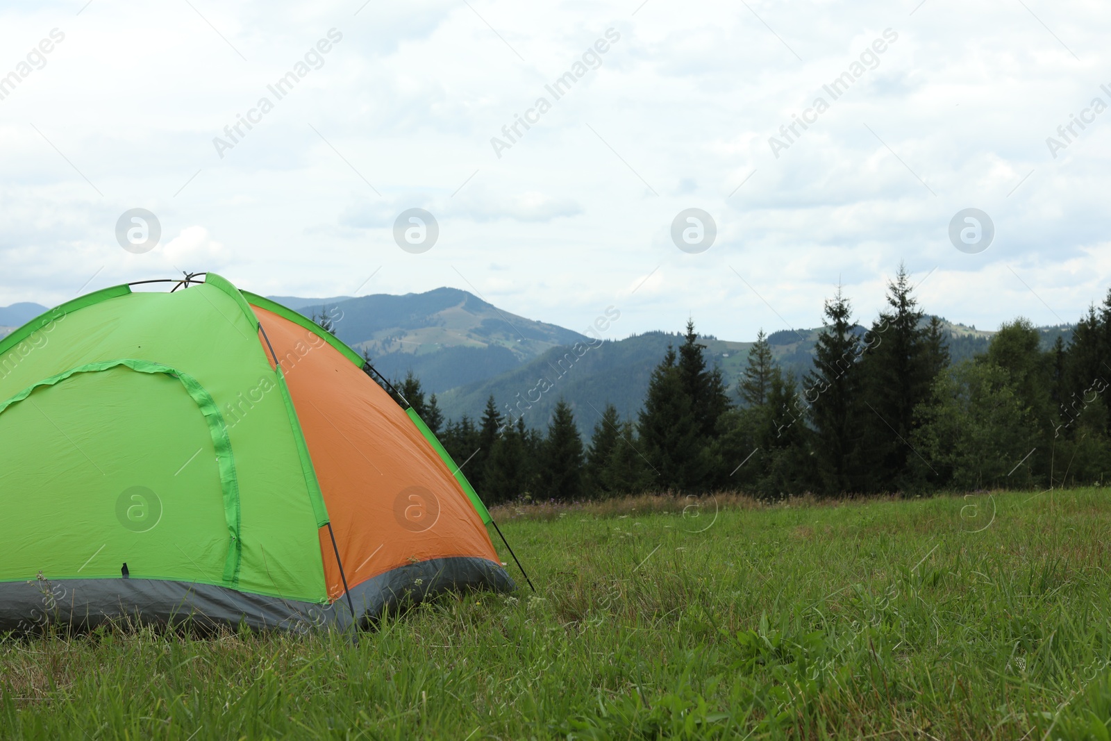 Photo of Tent on green grass in mountains, space for text