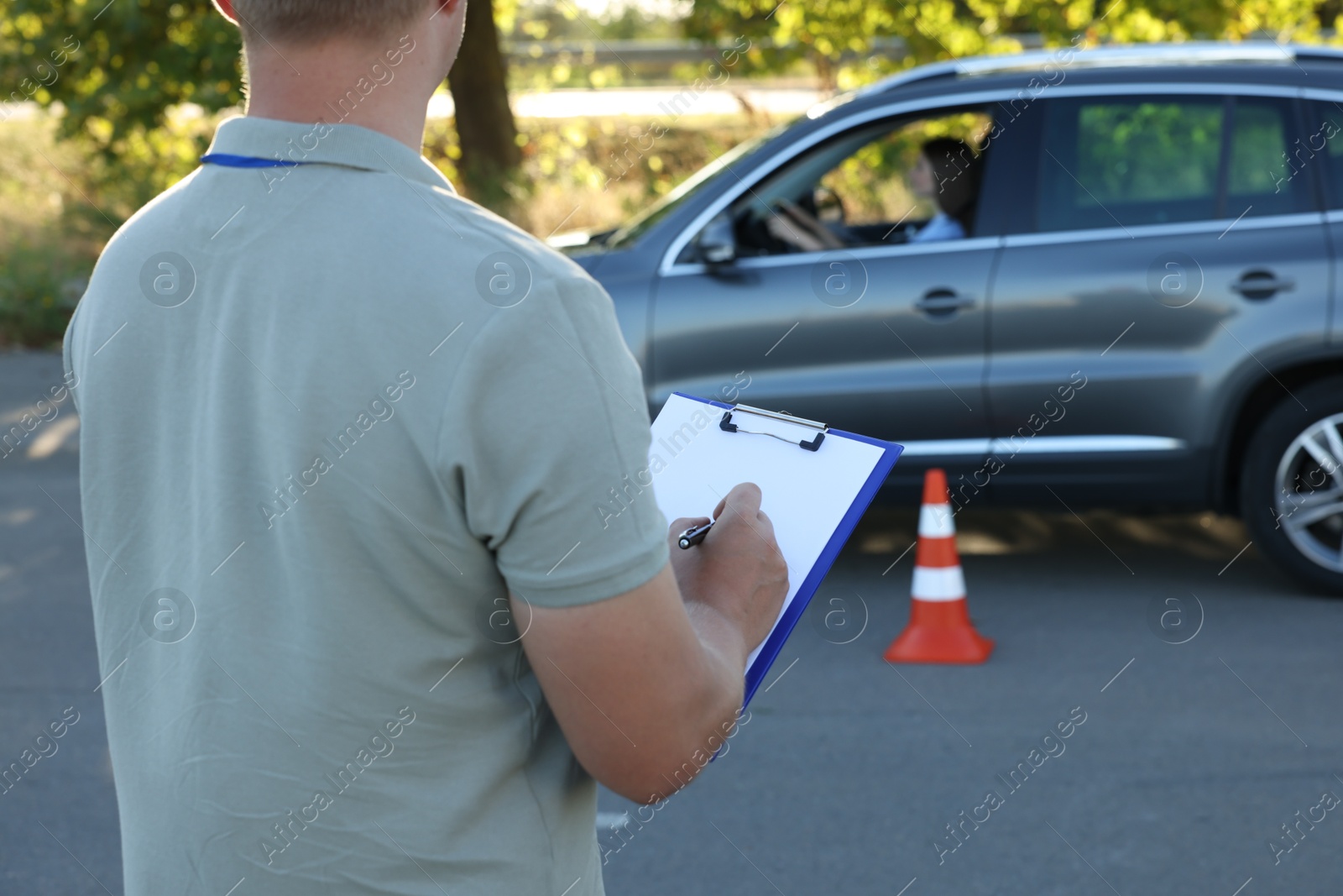 Photo of Examiner with clipboard during exam at driving school test track, closeup