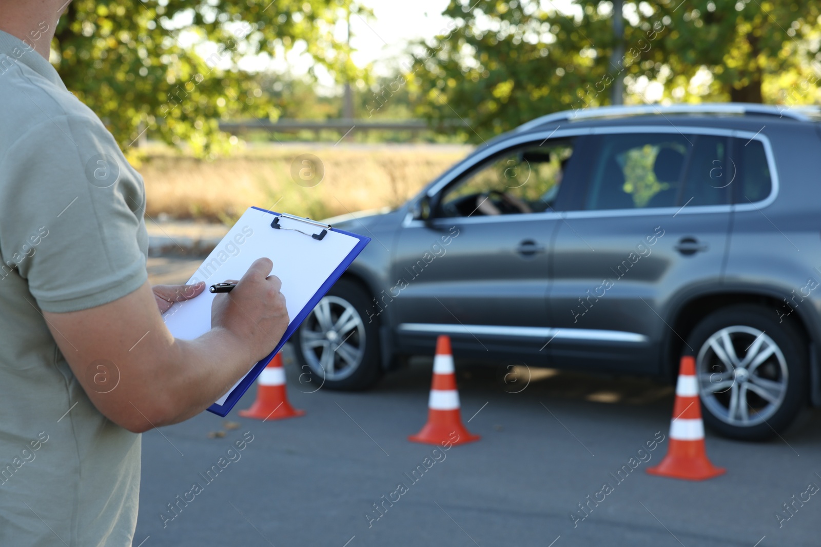 Photo of Examiner with clipboard during exam at driving school test track, closeup