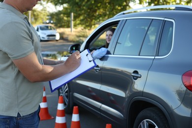 Photo of Examiner with clipboard during exam at driving school test track, closeup