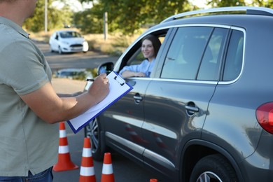 Photo of Examiner with clipboard during exam at driving school test track, closeup