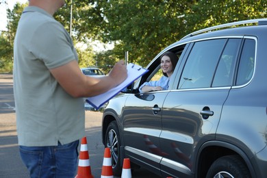 Examiner with clipboard during exam at driving school test track, closeup