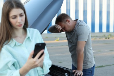 Man and woman near broken car outdoors, selective focus