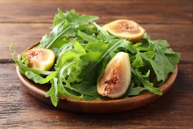 Photo of Fresh arugula and cut fig on wooden table, closeup